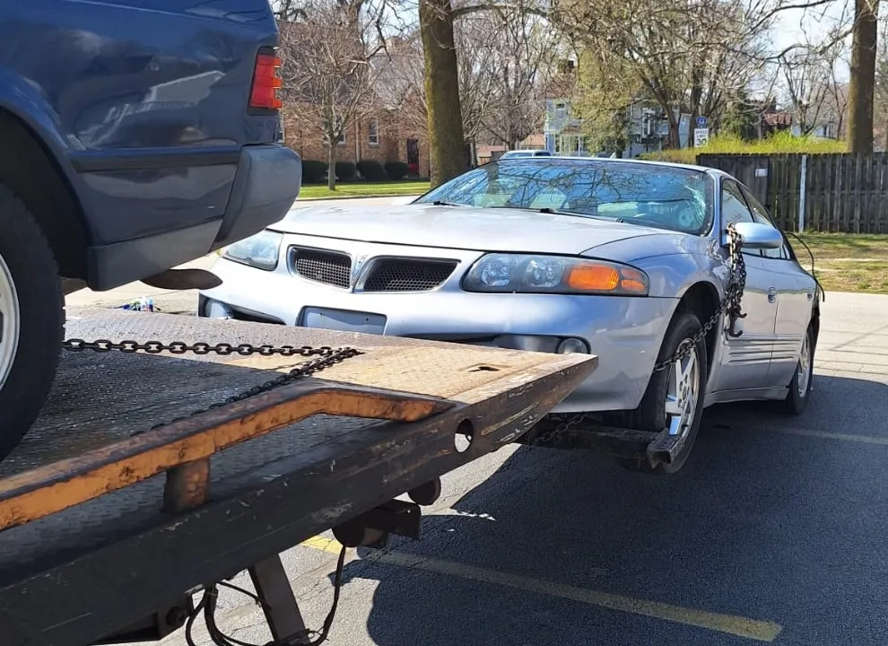 Silver sedan being winched onto the flatbed.